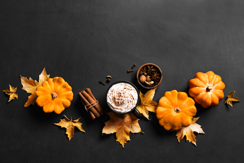 Pumpkin spice latte with mini pumpkins, spices, and autumn leaves