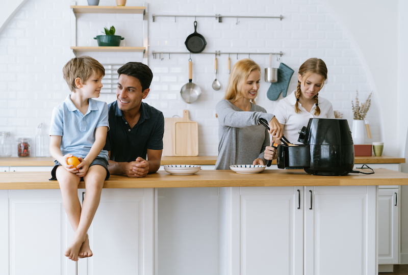 Family preparing food together with an air fryer in the kitchen