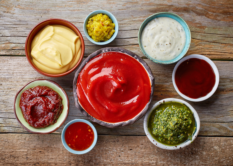 Assorted sauces and condiments in small bowls on a wooden table