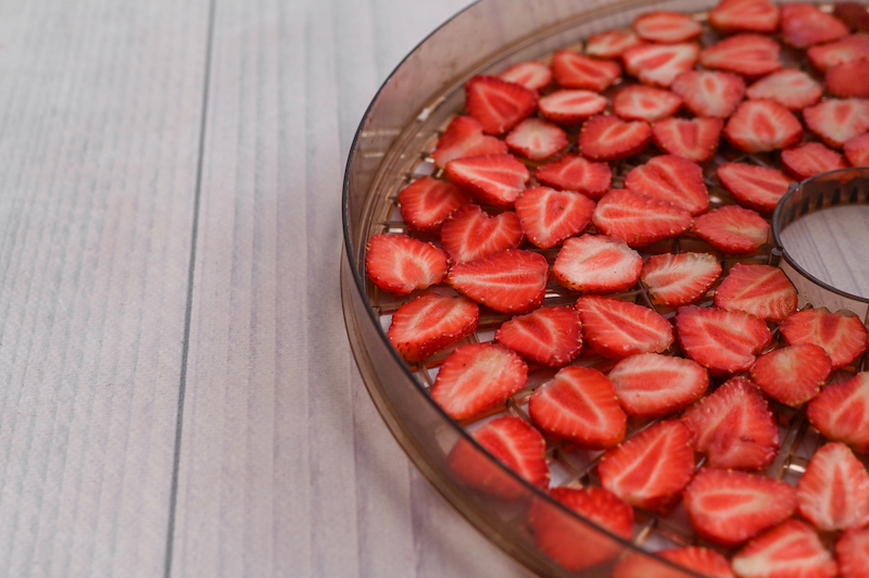 strawberry slices layered in a dehydrator