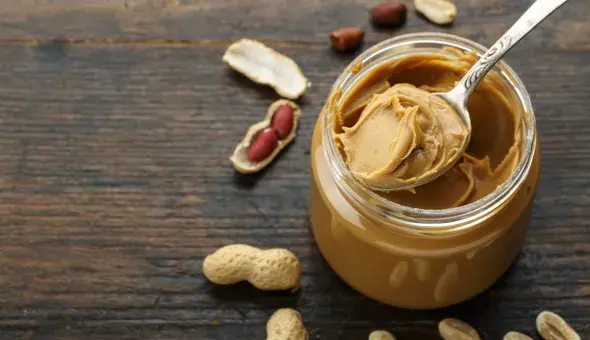 jar of peanut butter with spoonful sitting on top