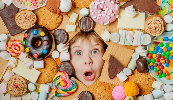 face of a child looking through a pile of sweet treats with a surprised expression