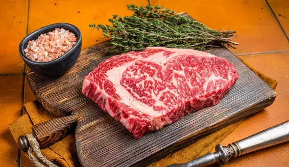 Wagyu steak on a cutting board with salt and thyme